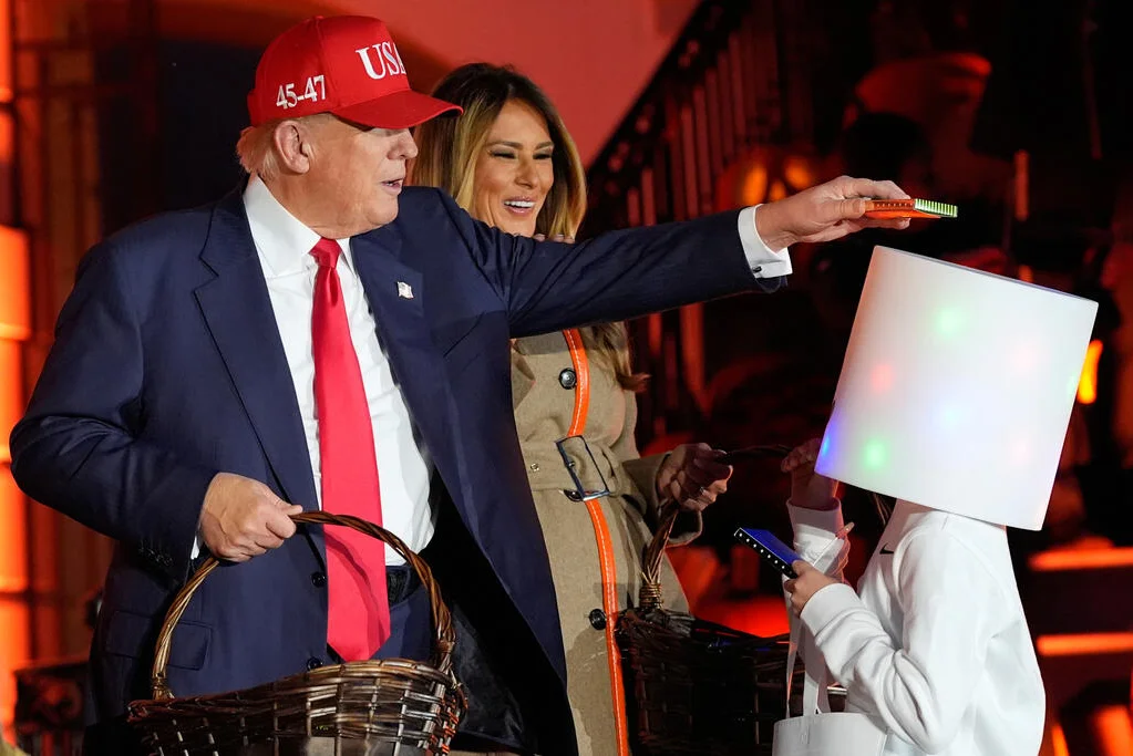 President Trump balances a piece of candy atop a trick-or-treater seemingly dressed as electronic DJ Mashmallo, reenacting a viral moment from the White House's 2019 Halloween party.